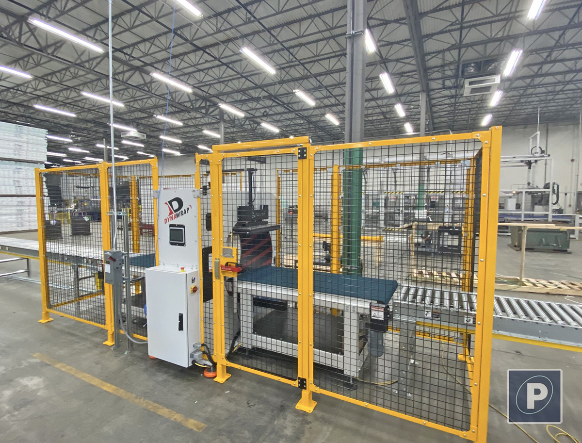 Dynawrap Pro 1100 orbital wrapper integrated into a yellow safety cell with motorized roller conveyors and a custom side-mounted HMI