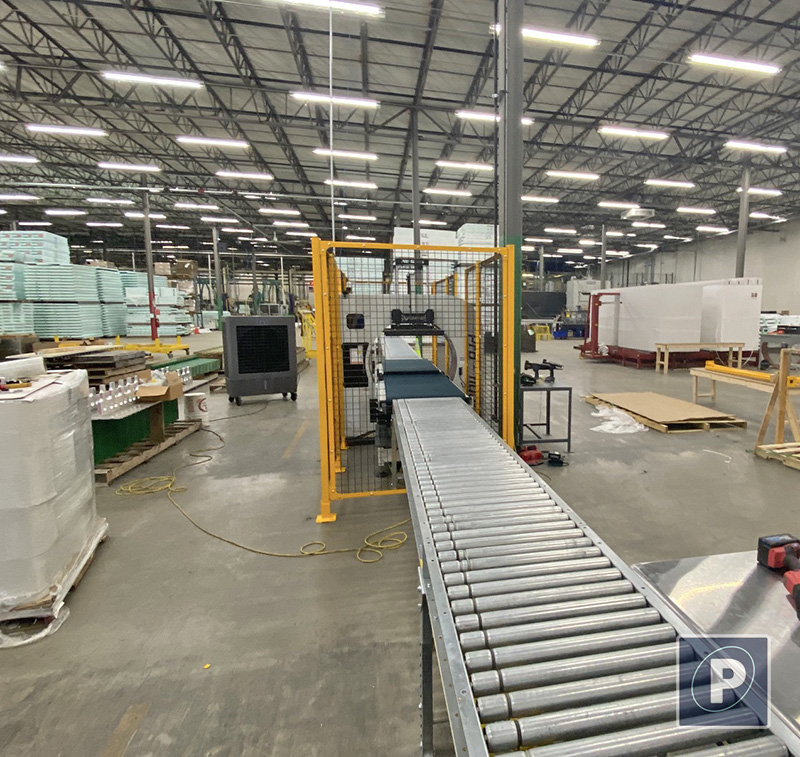 Infeed view of the Pro 1100 showing 10 feet of customer-integrated metal motorized roller conveyors feeding into the wrapping cell